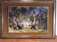 Framed landscape painting showing arrangement of gum trees and natural scene with velvet matting and wooden frame.