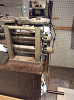 Front angle view of mill showing steel frame and cylindrical rollers on wooden platform