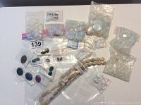 Overview of white opalite cabochons and beads, black opal slivers, and white Africa opal beads in small bags and plastic pouches