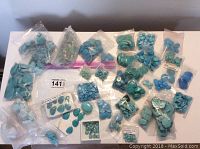 Overview of all bags of turquoise beads, cabochons, and rough stones spread out on a surface.
