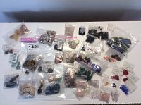 Overview showing the variety of assorted beads and cabochons in individual plastic bags spread out on a flat surface.