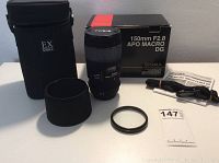 All included items arranged on table: lens, box, carrying case, hood, filter, manual, strap