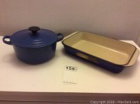 Photo showing round Dutch oven with lid and a rectangular roasting pan, both in Marseille Blue, placed side by side on a white surface