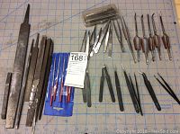 Full lot overview showing metal files on left, multiple tweezers and custom curved tools on right, with a plastic container.
