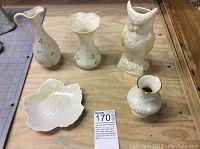 Overview of all five pieces including four vases and one owl figurine on wooden table.