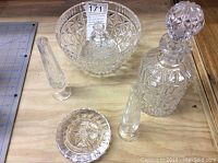 Full lot of Waterford cut glass items on wooden surface, showing decanter, ice bucket, candlesticks, and ashtray.