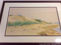Framed watercolor beach dune scene by D. L. Vickery showing sandy dunes and a small white house.