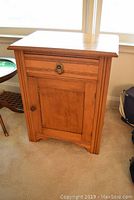 Front view showing single drawer with metal handle and cupboard door with wooden knob, wood finish wash stand.