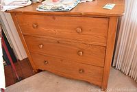 Front and side views of the refinished wooden dresser with three drawers featuring round wooden knobs, showing top surface and drawer fronts.