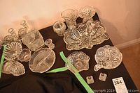 Overview of all vintage glass serveware items displayed on a surface including bowls, a small pitcher, candle holders, and salt and pepper shakers.