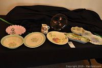 Overall display of vintage china serveware showing various bowls, trays, cream and sugar set, and decorative items in floral and pastel colors.