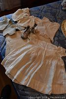 Full view of the vintage christening outfit items laid out including dress, sweaters, shoes, bibs, and shawl.