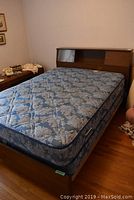 Mid century double bed showing entire bed with mattress on wooden frame in room corner.