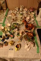Top view of the assorted collection of porcelain and ceramic figurines, miniatures, teacups, and egg cups arranged on a table