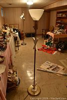 Full view of mid century floor lamp with glass shade in basement setting with other items around