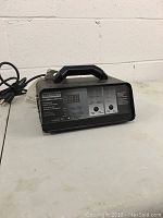 Front and side view of Eliminator intelligent battery charger showing digital display and labeled buttons.