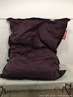 Front view of the full size purple Fat Boy bean bag chair showing its rectangular, cushioned shape with red brand tag.