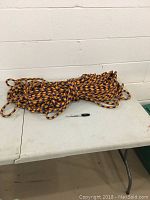 Coiled climbing rope laid on a white folding table with a black Sharpie marker for scale against a white cinder block wall background.