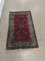 Full view of the antique Persian Kerman rug, showing overall pattern and colors on a light floor.