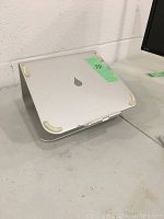 First laptop stand, silver aluminum with curved design and four off-white rubber pads on top to prevent slipping and protect laptop.