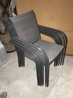 Stacked black patio chairs showing metal frames and mesh seating and backs