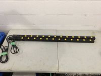 Two black 12-outlet power bars laid flat on a table, showing the outlets and attached power cords.