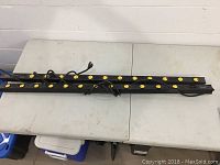 Two black power strips with 12 yellow outlets each placed on a table, power cords visible, tested and working.