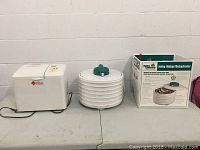 Wide view showing Regal bread maker, Open Country jerky maker/dehydrator, and the jerky maker's original box on table.