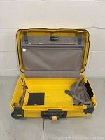 Open yellow hard shell suitcase showing interior fabric lining and zipped pocket on lid.