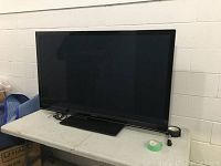 Front view of 55in Panasonic Viera plasma HDTV on table with cables and tape rolls