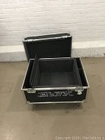 Open black hard travel case showing foam-padded interior large main compartment and smaller section on the side.