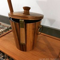 Photo of mid-century modern teak ice bucket with brass latch and ring handles, including a fitted lid with knob handle.