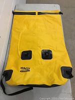 Full view of the folded yellow SeaLine Boundary 115 waterproof backpack showing material, straps, and valve-like features.