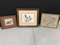 Three framed artworks on black background, including a map, duck print, and house watercolor print.
