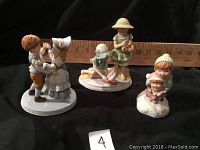 Three collectible figurines: two pairs of children in vintage-style clothing and one winter-themed musical figurine of a boy hugging a girl