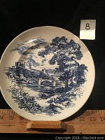 Front view of blue and white glazed countryside scene plate showing hand engraved details and measuring approximately 7 inches in diameter.