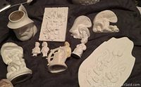 Wide photo showing all bisque pottery pieces together on dark background.