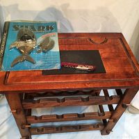 Wooden wine rack with black inset top surface, new vintage shark corkscrew in packaging, and red Banff Wine Store corkscrew on top