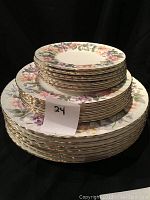 Stack of plates showing multiple sizes with colorful floral pattern and gold trim, highlighting the set of 7 plates.