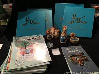 Lot of PenDelphin figurines with collector plates and books visible behind.