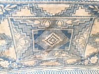 Close-up of thick white and blue patterned wool blanket with geometric and floral motifs.
