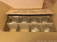 Open cardboard box showing six hexagonal glass jars arranged in two rows of three within cardboard dividers.