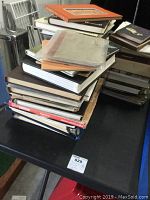 Stack of multiple vintage car themed books and manuals, showing spines and covers of various titles related to classic cars.