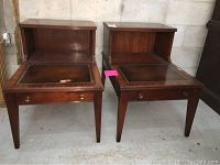 Two vintage wooden nightstands shown side by side, dark finish, leather inset tops, brass drawer pulls