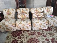 Four floral upholstered side chairs arranged in a row with two matching floral pillows on two chairs, showing skirted design and fabric pattern.