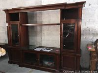 Full frontal view of large Bernhardt cherry wood entertainment center with glass display cabinets and base cabinets with glass doors.