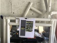 Unassembled white PVC pipe components arranged with an assembly instruction sheet attached to the frame.