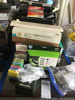 Photo showing 9x12 inch catalog envelopes, packaged HP 940 ink cartridges in multiple colors, sticky notes, and miscellaneous small office items.