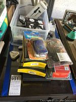 Image showing various electronic accessories including Remington Micro shaver, packaged earphones, chargers, and travel adapters in plastic bins and stacked on a table for sale