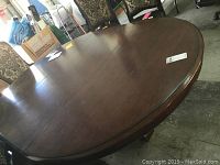 Top surface of the oval-shaped Bernhardt table with cherry stain finish showing some light scratches and a label.